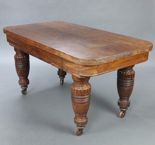 A Victorian rectangular oak dining table raised on turned and reeded supports with brass caps and ceramic casters 75cm h x 148cm w x 80cm d 