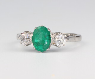 A white metal stamped Plat. oval emerald and diamond ring, the centre oval emerald 1.1ct, the 2 brilliant cut diamonds 0.55ct, 5.1 grams, size P 
