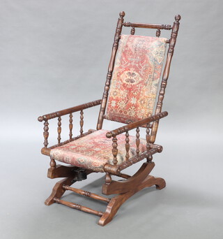 A 19th Century American turned mahogany rocking chair, the seat and back upholstered, raised on turned supports 106cm h x 53cm w x 58cm d 