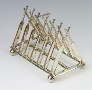 A silver plated novelty 7 bar toast rack in the form of crossed cricket bats on ball feet 