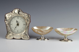 A modern repousse silver battery timepiece 20cm, together with a pair of silver mounted shell salts (1 af) 