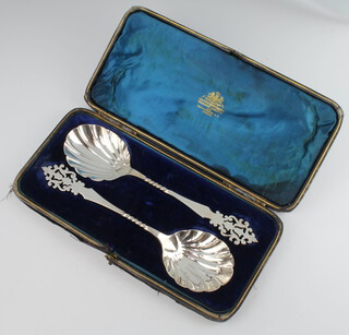 A pair of Edwardian silver serving spoons with shell bowls and pierced handles, London 1902, cased 148 grams