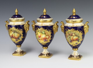 A set of 3 20th Century Coalport blue ground twin handled urns and covers with panels decorated fruit, raised on square bases 24cm h 
