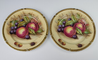 Aynsley, a pair of plates decorated peaches and grapes with gilt borders 26cm, signed D James  