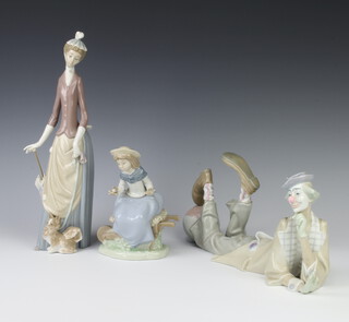 A Lladro figure of a reclining clown, impressed Lladro, Made in Spain 36cm l, a  Lladro figure of a lady with parasol and dog 36cm  together with a Nao figure of  girl sat on a wheelbarrow 17cm