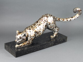 A resin figure of a crouching cheetah raised on a marble base 27cm x 55cm x 19cm 