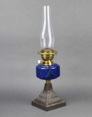 A Victorian oil lamp with blue glass reservoir raised on a waisted metal base 30cm h x 14cm w x 14cm d 
