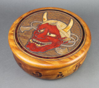 A Japanese circular carved hardwood bowl and cover, the lid decorated a horned figure, interior decorated a toad and hare 12cm h x 34cm diam.
