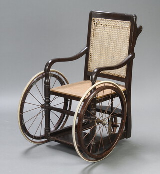 An Edwardian cane and beech wheelchair marked Surgical manufacturing Company Ltd, Surgical Instrument Manufacturers 83-85 Mortimer Street 105cm h x 63cm w x 75cm d (seat 32cm x 36cm) 