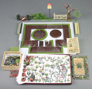 A quantity of 1930's Britains miniature garden series lead models including flower beds, flowers, tree with gate, stile, balustrade, dovecote etc and an unopened waxed paper bag containing tulips no.041