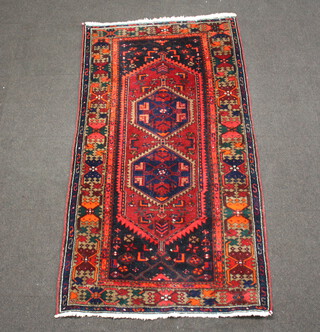 A red and blue ground Afghan rug with 2 diamonds to the centre within a multi row border 201cm x 100cm 