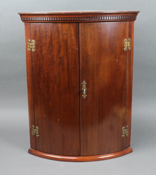 A Georgian style mahogany bow front hanging corner cabinet with moulded and dentil cornice, fitted shelves enclosed by a panelled door 65cm h x 52cm w x 36cm d 