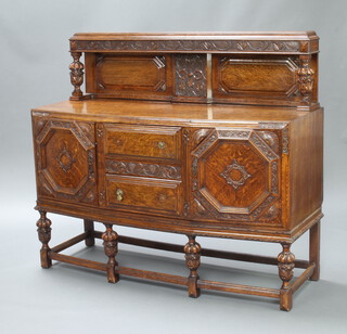 A 1930's carved oak sideboard with raised back supported by cup and cover supports, the base fitted 2 drawers and a secret drawer flanked by cupboards, raised on cup and cover supports 132cm h x 151cm w x 51cm d   