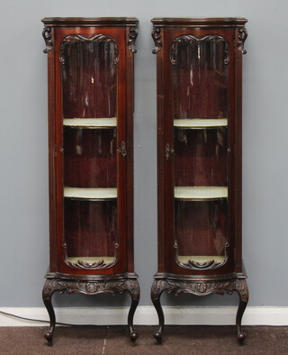 A pair of Edwardian carved mahogany bow front cabinets fitted shelves enclosed by panelled doors, raised on 2 carved cabriole supports (formerly part of a display cabinet) 114cm h x 41cm w x 54cm d 