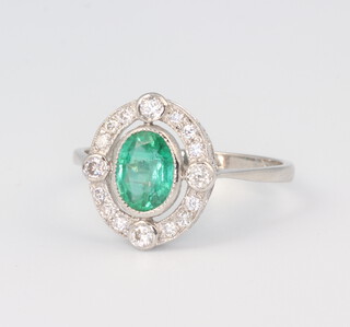 A white metal stamped Plat. oval emerald and diamond ring, the centre stone 0.6ct, the brilliant cut diamonds 0.5ct, size N, 3.3gms 