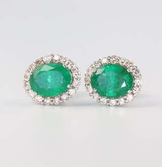 A pair of white metal oval emerald and diamond ear studs, the centre stones 3.8ct, the brilliant cut diamonds 0.78ct, 4gms, 12mm x 10mm 