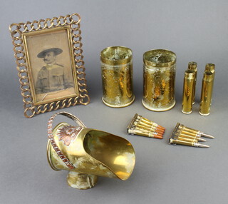 A copper and brass Trench art sugar scuttle formed from a shell with the cap badge of the Australian Commonwealth Military Force 10cm h x 14cm w x 9cm d, 2 First World War Trench Art vases formed from shells, bases marked Berndorf 1916 and 1917 13cm x 7.5cm, 2 clips of training rounds and 4 cannon shells together with a brass easel photograph frame 23cm x 16cm (glass f)  