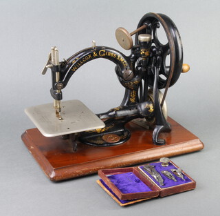 A Wilcox and Gibbs manual sewing machine together with various attachments contained in a leather box 
