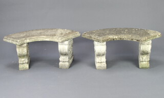 A pair of well weathered crescent shaped concrete garden benches raised on scrolled supports 42cm h x 100cm w x 36cm d 