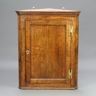 A Georgian oak hanging corner cabinet with moulded cornice enclosed by a panelled door with H framed brass hinges 90cm h x 73cm w x 50cm d 