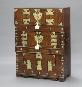 A Chinese hardwood and metal mounted cabinet with brass carrying handles to the sides, the top section fitted 6 short drawers enclosed by panelled doors above a cupboard enclosed by panelled doors, the lower part fitted 1 long drawer, with a short drawer to either side, the base with fall front 110cm h x 81cm w x 38cm d 