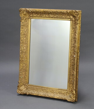 A 19th Century rectangular plate mirror contained in a decorative gilt plaster frame 111cm h x 79cm w x 9cm d 