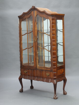 A French style arched walnut display cabinet fitted shelves enclosed by astragal glazed panelled doors, the base fitted a drawer, raised on cabriole supports 181cm h x 95cm w x 40cm d 