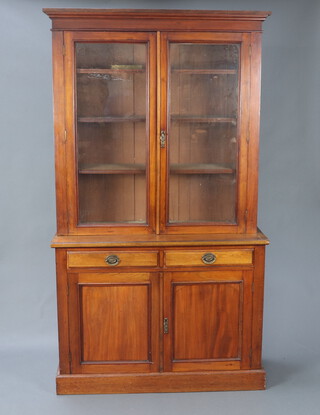 A Victorian mahogany bookcase on cabinet with moulded cornice, fitted shelves enclosed by glazed panelled doors, the base fitted 2 short drawers above cupboard enclosed by panelled door 212cm h x 119cm w x 43cm d 