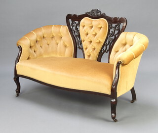 An Edwardian pierced and ebonised show frame sofa upholstered in gold buttoned material, raised on cabriole supports 92cm h x 184cm w x 59cm d (seat 107cm x 36cm) 