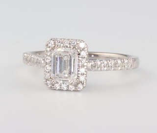 An 18ct white gold diamond ring, the centre emerald cut stone approx. 0.7ct surrounded by brilliant cut diamonds and diamond shoulders, total weight 1.14ct, size M, 3.7 grams (with WGI certificate) 