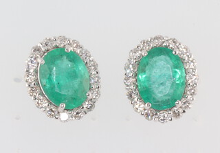 A pair of white metal 18k oval emerald and diamond ear studs, the emeralds approx. 3.3 ct, the brilliant cut diamonds 0.16ct, 4.2 grams, 13mm x 10mm 