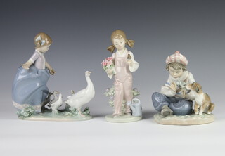A Lladro figure of a seated boy and puppy 14cm, a ditto of a girl with bird 5217 18cm and a ditto of a girl with a family of geese 19cm 