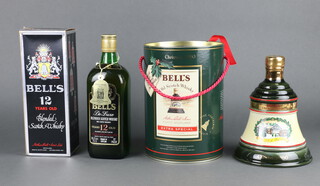 A 75.7cl bottle of Bells 12 year old deluxe blended Scotch whisky, boxed together with a 1990 75cl Christmas Bell shaped decanter of whisky 