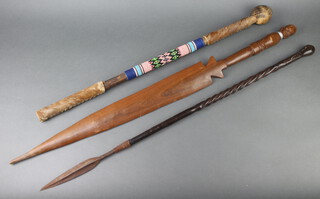 A Zulu dance spear with 17cm leaf shaped blade, the spiral turned lignum vitae shaft marked UVONGO, together with a carved African double bladed dance spear 95cm, an African club/cane with hide and bead decoration 87cm 