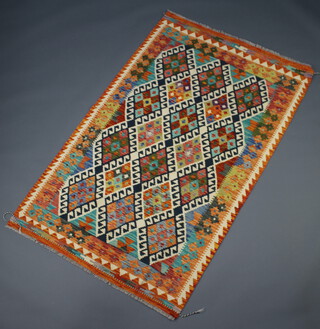 An orange, green, black and white ground Chobi Kilim rug with all over geometric design 203cm x 127cm 