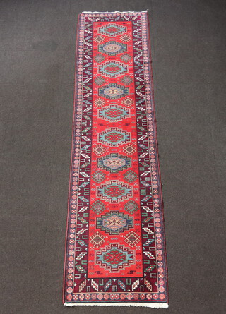 An Afghan red, green and brown ground runner with 10 medallions to the centre 336cm x 81cm 