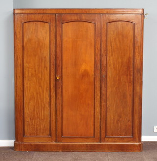A Victorian mahogany triple wardrobe with moulded cornice, the left hand section fitted 3 trays above 2 short and 2 long drawers enclosed by a pair of arched panelled doors, the right hand section fitted a hanging space 200cm h x 179cm w x 59cm d 