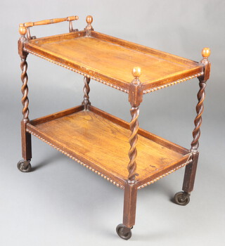 A 1930's rectangular oak 2 tier tea trolley raised on spiral turned supports 76cm h x 81cm w x 42cm d 