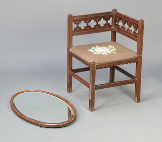 A Gothic style carved mahogany corner chair with Berlin walnut seat, raised on square supports with box framed stretcher 66cm h x 43cm w x 43cm d  together with a 1930's oval bevelled plate wall mirror in an oak frame 71cm x 44cm 