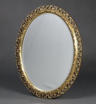 An oval bevelled plate wall mirror contained in a decorative gilt frame 72cm h x 56cm w