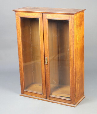A 1930's oak bookcase/display cabinet fitted adjustable shelves enclosed by glazed panelled doors 107cm h x 79cm w x 31cm d 