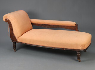 An Edwardian carved mahogany show frame chaise longue upholstered in orange material, raised on turned supports 75cm h x 162cm w x 60cm d (seat 110cm x 41cm)  