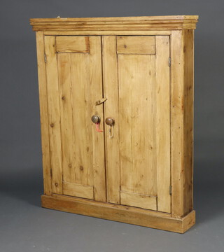 A 19th Century pine cabinet with moulded cornice, fitted shelves enclosed by panelled doors 134cm h x 115cm w x 21cm d 