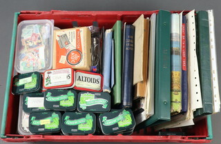 A collection of used GB and world stamps contained in albums and metal tins, all in a red plastic crate 