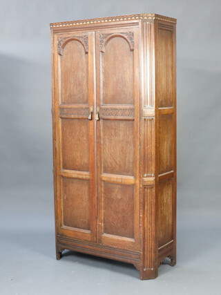 A carved oak hall wardrobe enclosed by arched panelled doors 183cm h x 92cm w x 42cm d (sun bleached) 