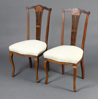 A pair of Edwardian inlaid mahogany stick and rail back dining chairs with over stuffed seats, raised on cabriole supports 97cm h x 46cm w x 39cm d 
