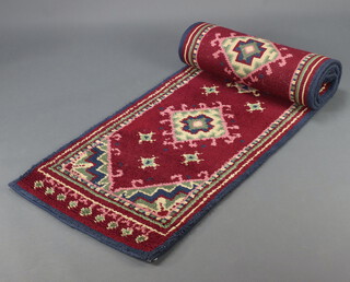 A red, white and green ground rag style rug runner with 5 diamonds to the centre 294cm x 61cm 