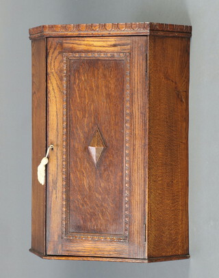 A 1920's oak hanging corner cabinet, fitted shelves enclosed by a panelled door 70cm h x 52cm w x 38cm d 