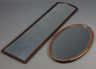 A 1930's arched plate mirror contained in a walnut frame 125cm x 33cm together with an oval bevelled plate mirror in an oak frame 32cm x 44cm 