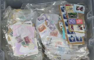 A collection of various used world stamps on paper contained in a transparent crate
